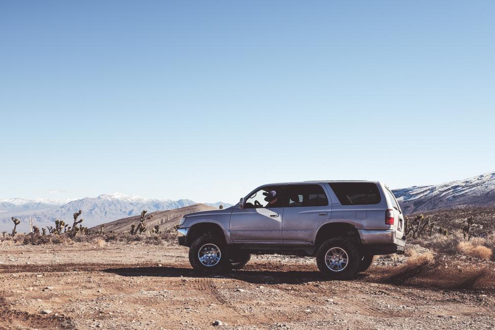Free Image of SUV driving through rugged terrain in mountainous landscape 