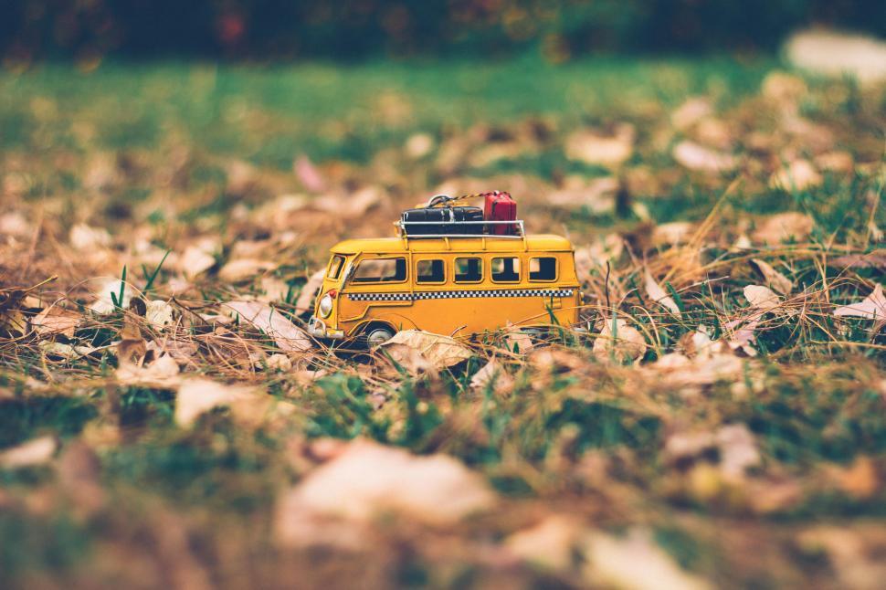 Free Image of Yellow toy van parked among autumn leaves in a natural setting 