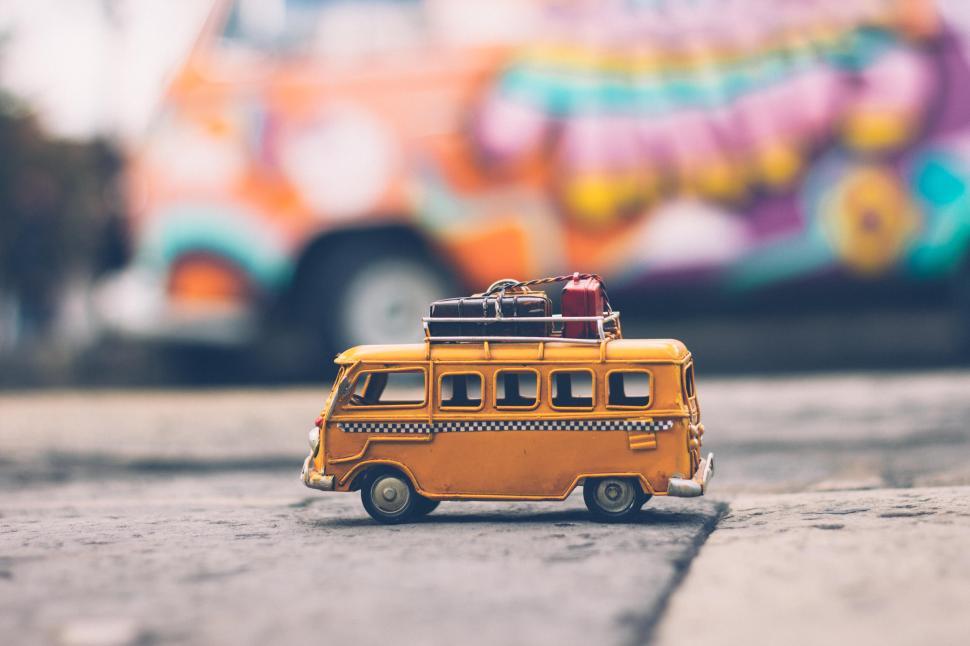 Free Image of Colorful model taxi van on cobblestone street with mural backdrop 