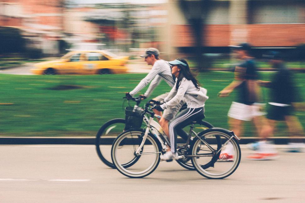 Free Image of Cyclists riding through urban park in lively city setting 