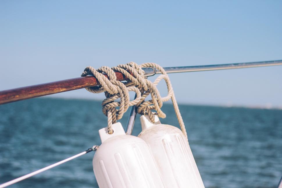 Free Image of Ropes and buoys secure a sailboat on a calm sea 