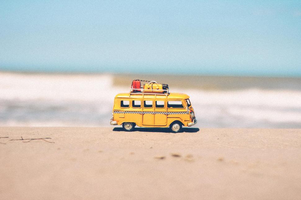 Free Image of Yellow toy van on sandy beach near ocean waves during daylight 