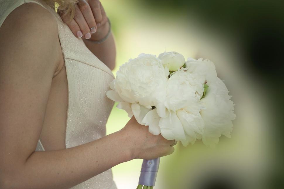 Free Image of Bride holding bouquet of white peonies in garden setting 