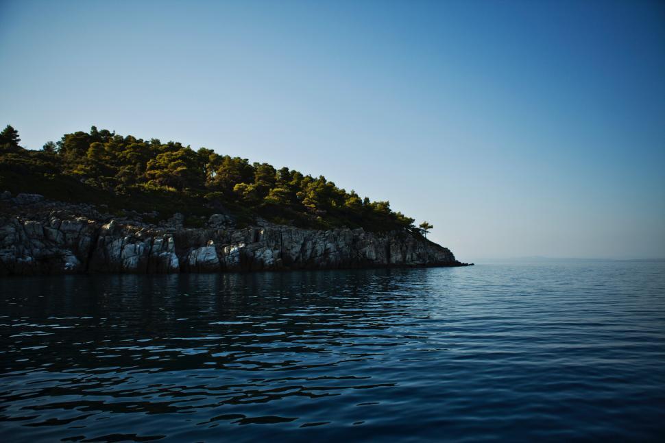 Free Image of Coastal view of rocky shoreline on a calm water day 
