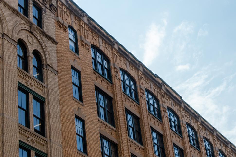Free Image of Historic brick building with large windows against a blue sky 