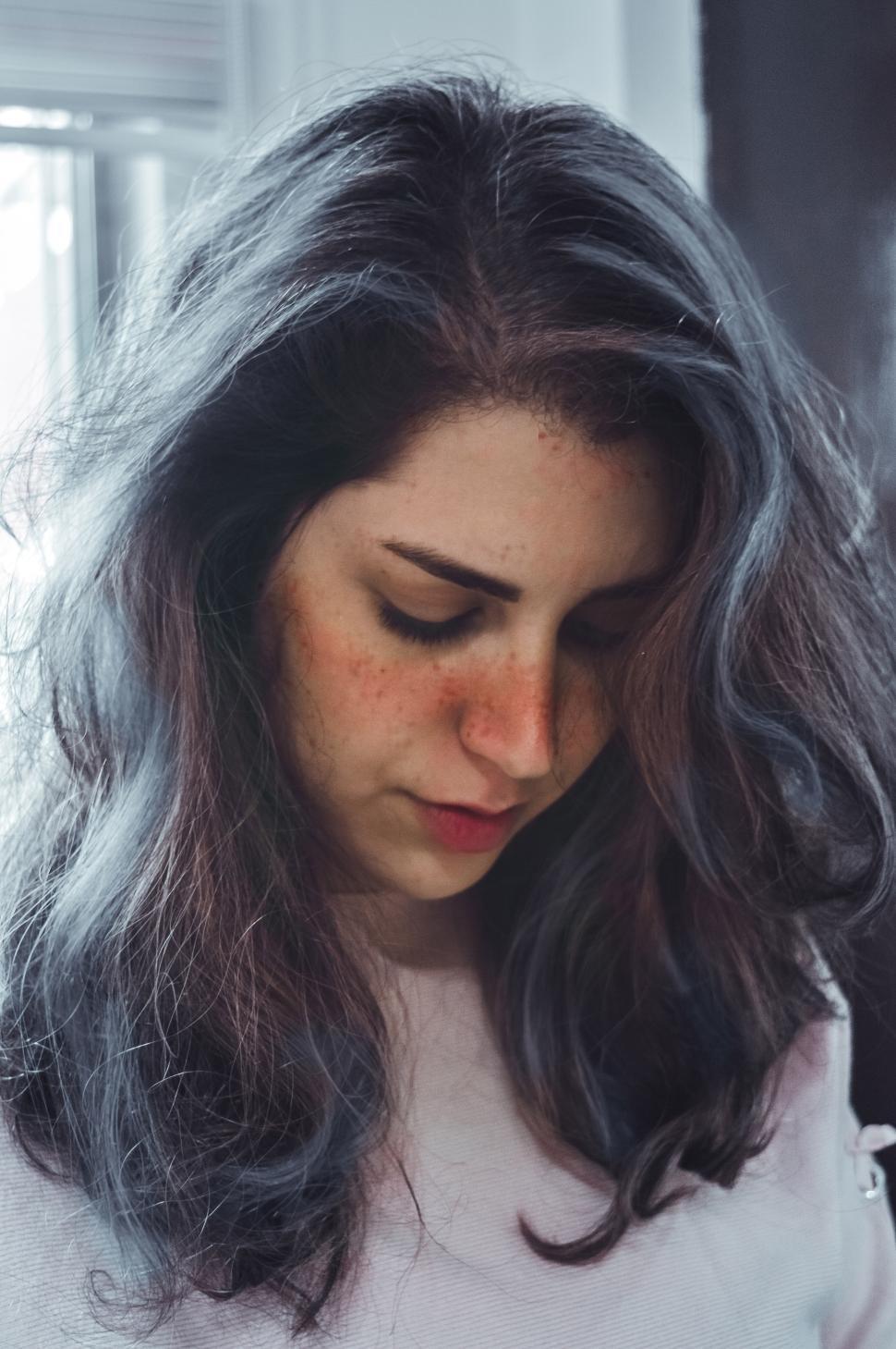 Free Image of Young woman with hair gazes down in sunlight 