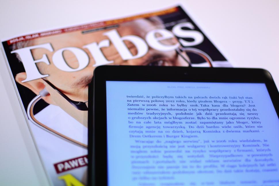 Free Image of Digital reading on tablet with magazine in the background 