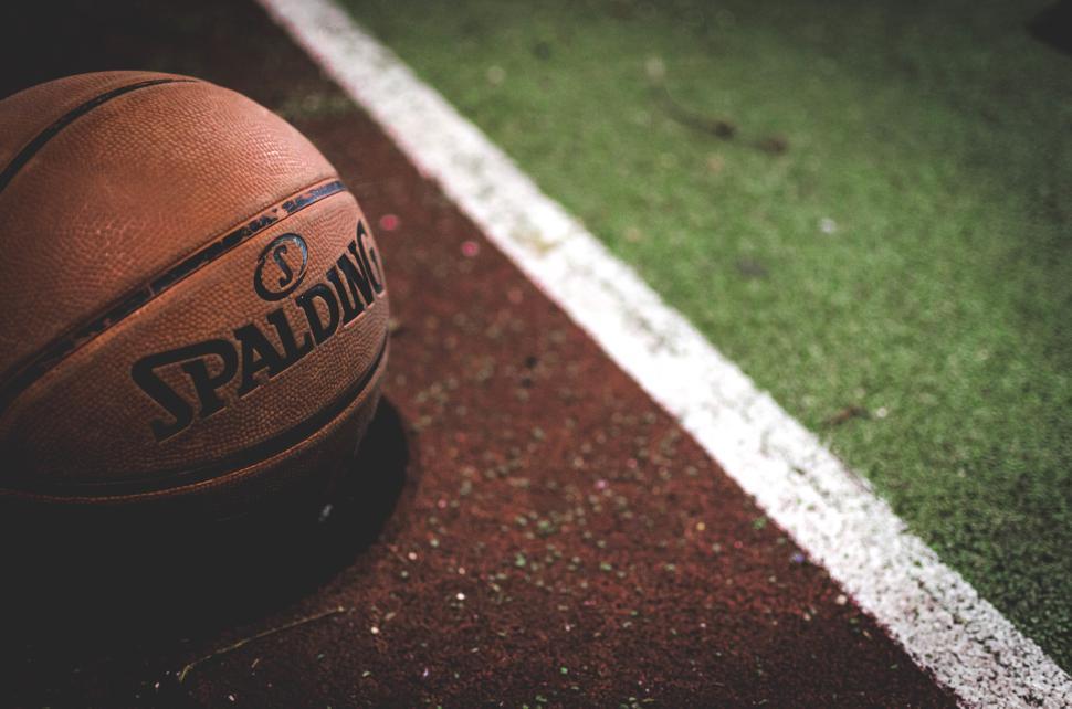 Free Image of Basketball resting on the edge of a court during evening practice session 