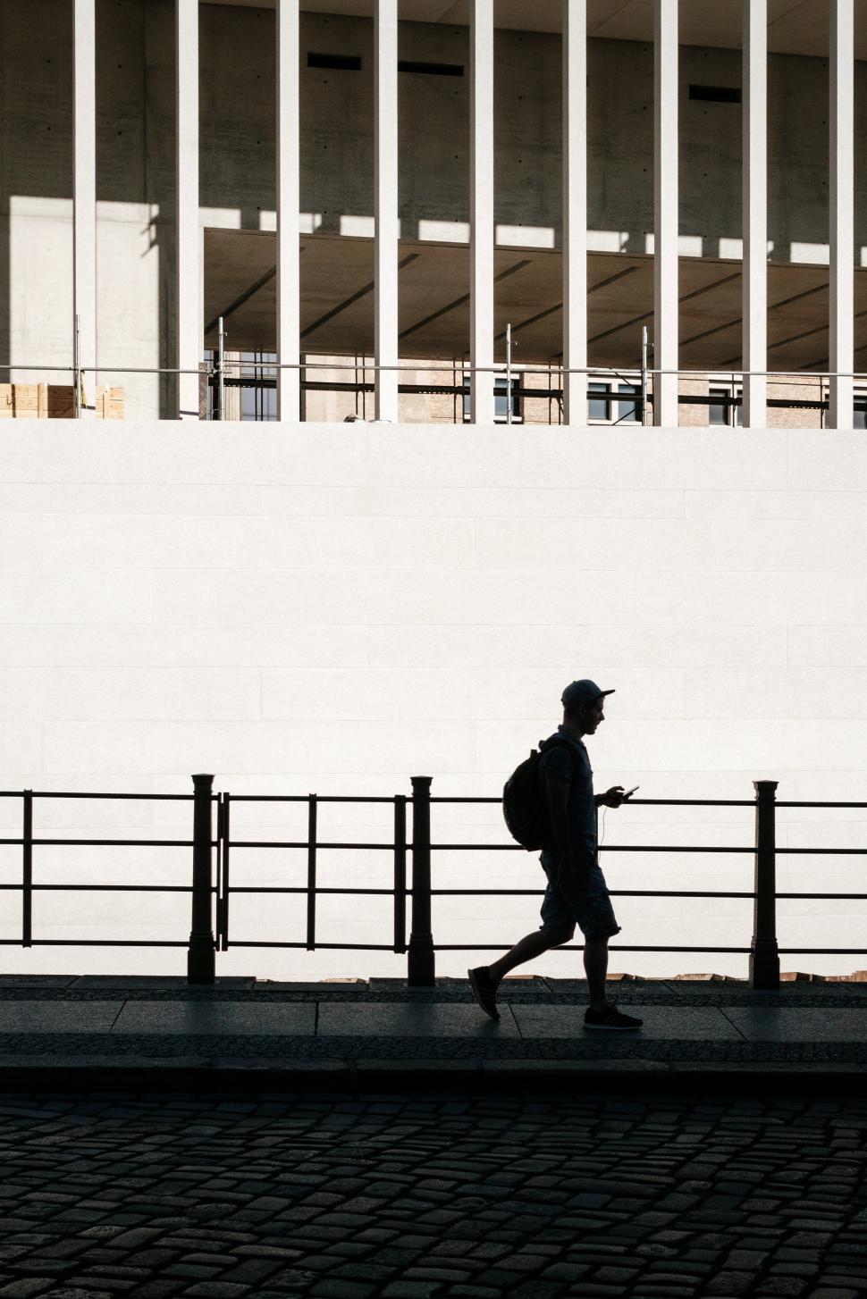 Free Image of Person walking in silhouette by modern building in urban setting 
