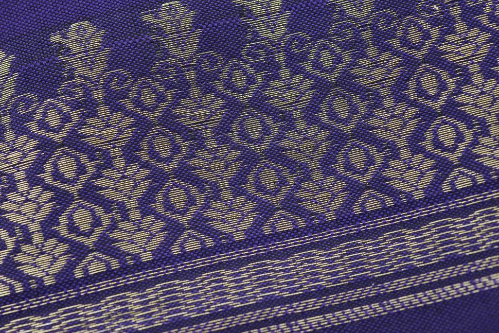 Free Image of Close-up view of a luxurious purple fabric adorned with detailed gold embroidery 