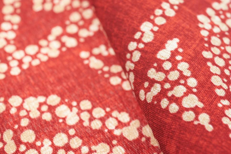 Free Image of Colorful red fabric with unique white patterns on display in a textile shop 