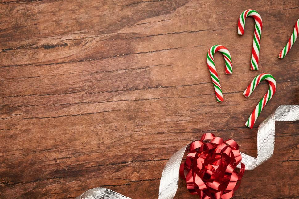 Free Image of Festive candy canes and gift ribbon on wooden table 
