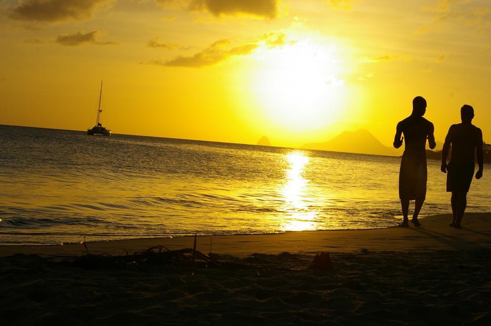Free Image of Two People Walking on a Beach at Sunset 
