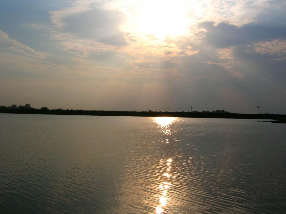 Free Image of Sunlight Peeking Through Clouds Over Water 