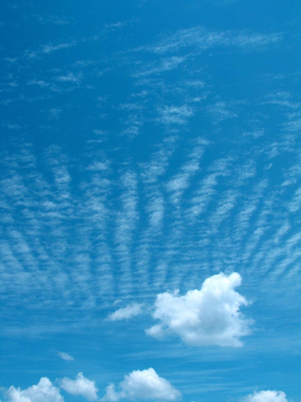 Free Image of A Plane Flying Through a Blue Sky With Clouds 