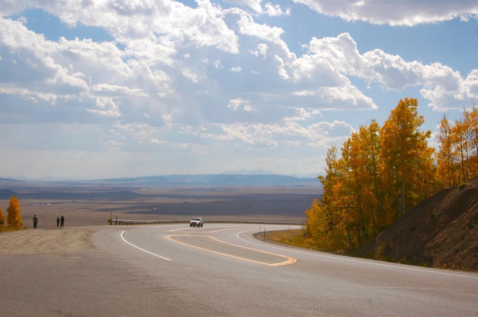 Free Image of The Billowing Clouds over a Fall Foliage Roadway 