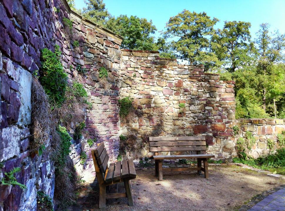 Free Image of Two park benches before a historical wall ruin 