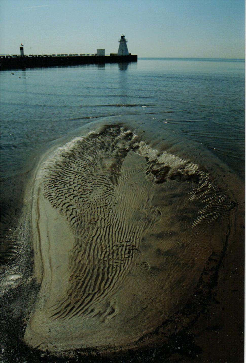 Free Image of A Large Body of Water With a Lighthouse in the Distance 