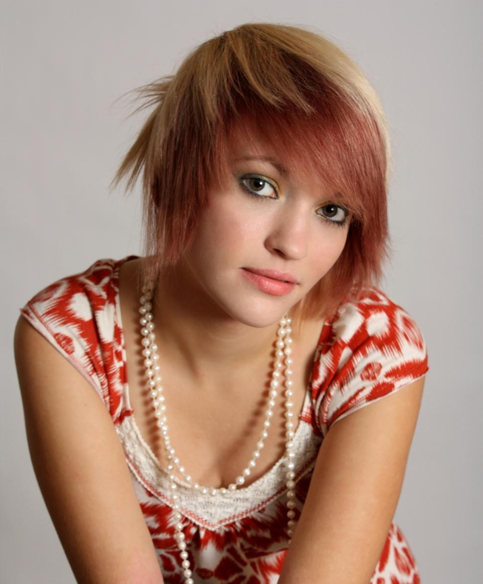 Free Image of A beautiful young woman wearing pearls posing on a gray background 