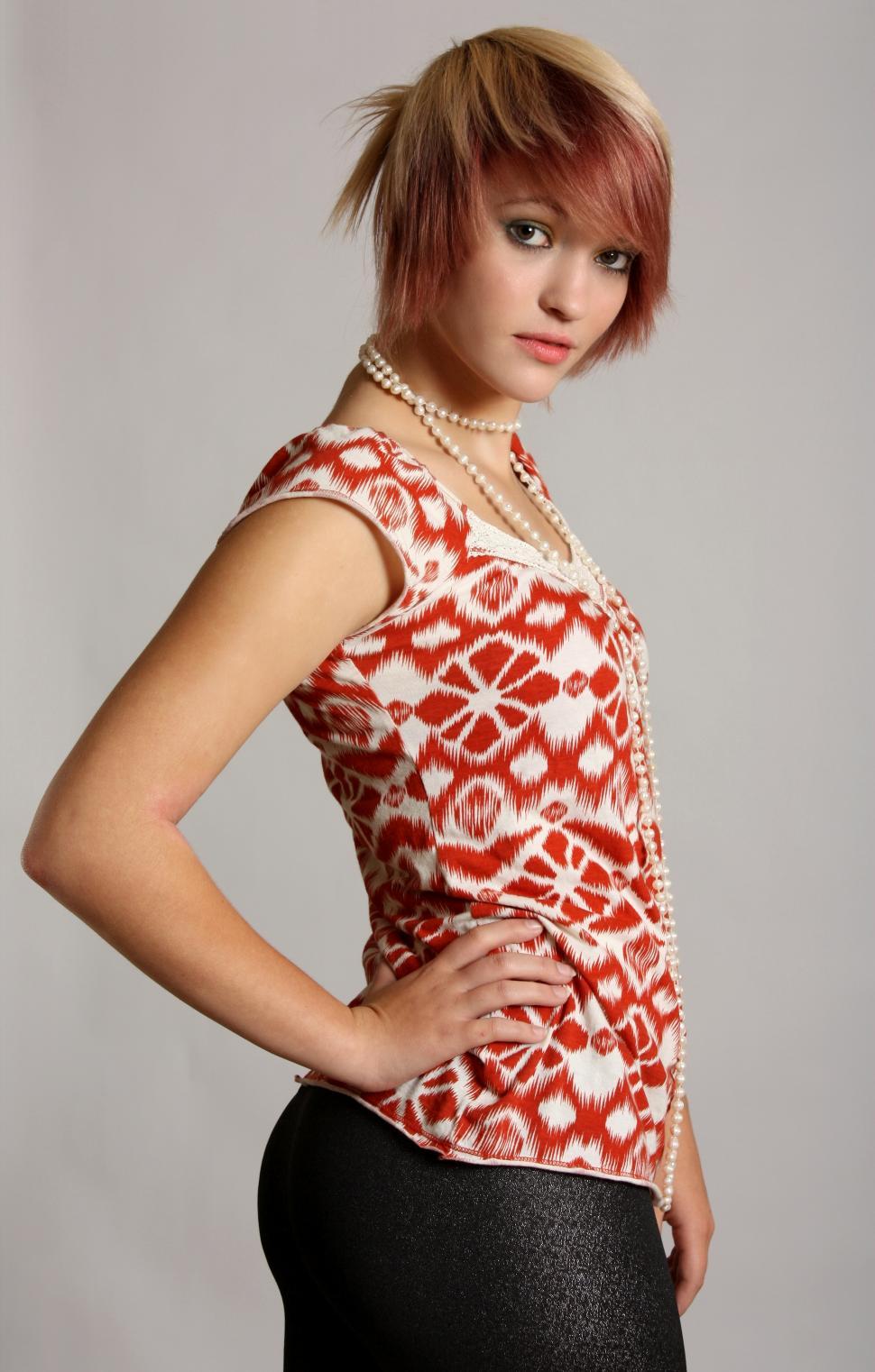 Free Image of A beautiful young woman wearing pearls posing on a gray background 