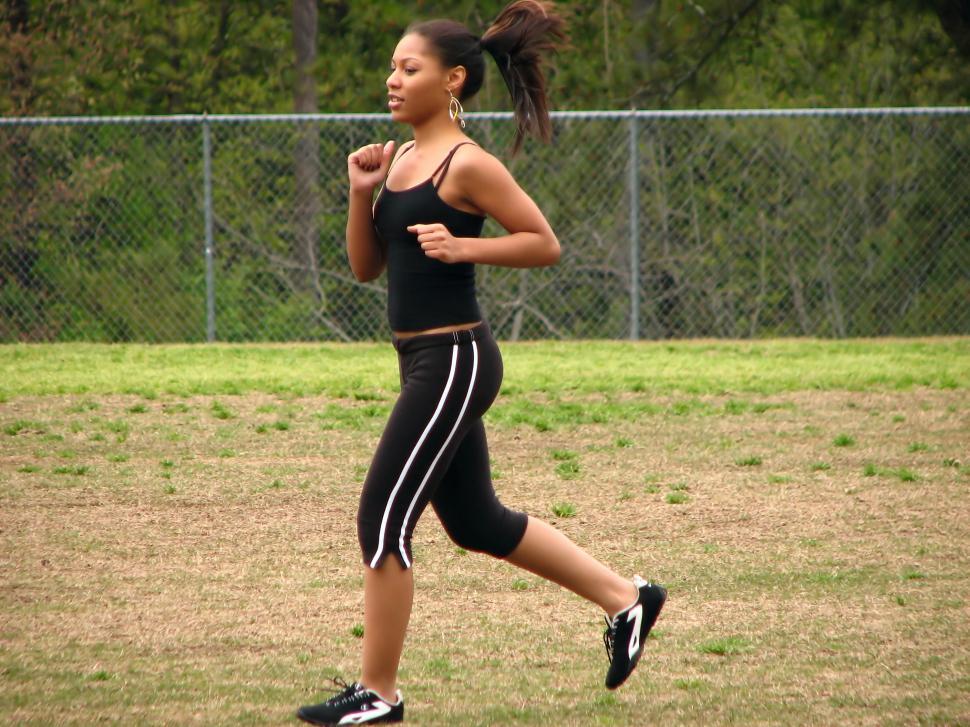 Free Image of A beautiful teen African American girl running by a fence 