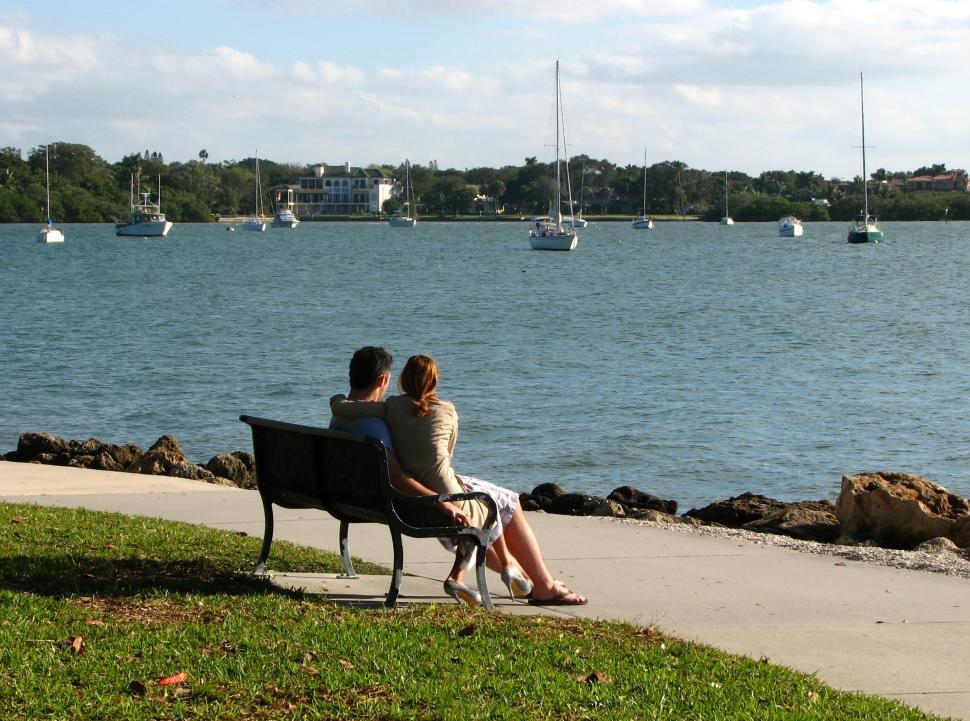 Free Image of A couple sitting on a bench overlooking the ocean 
