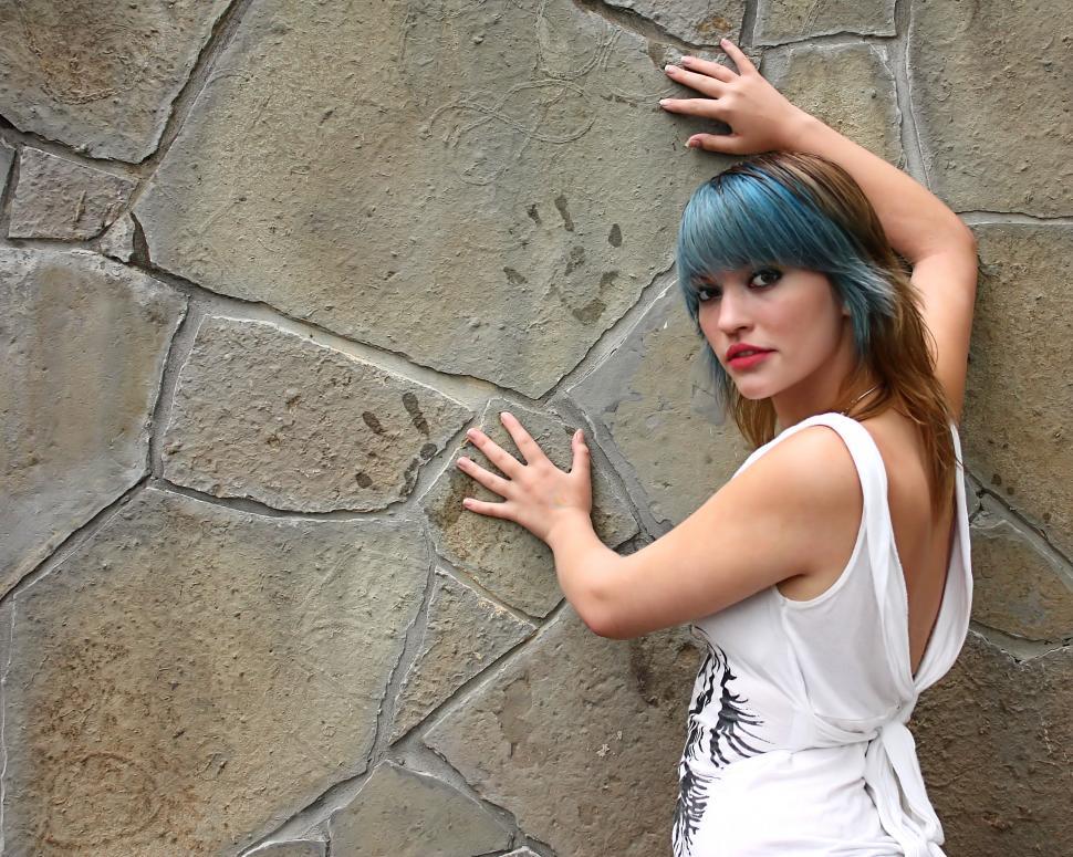 Free Image of A beautiful young woman posing against a stone wall 