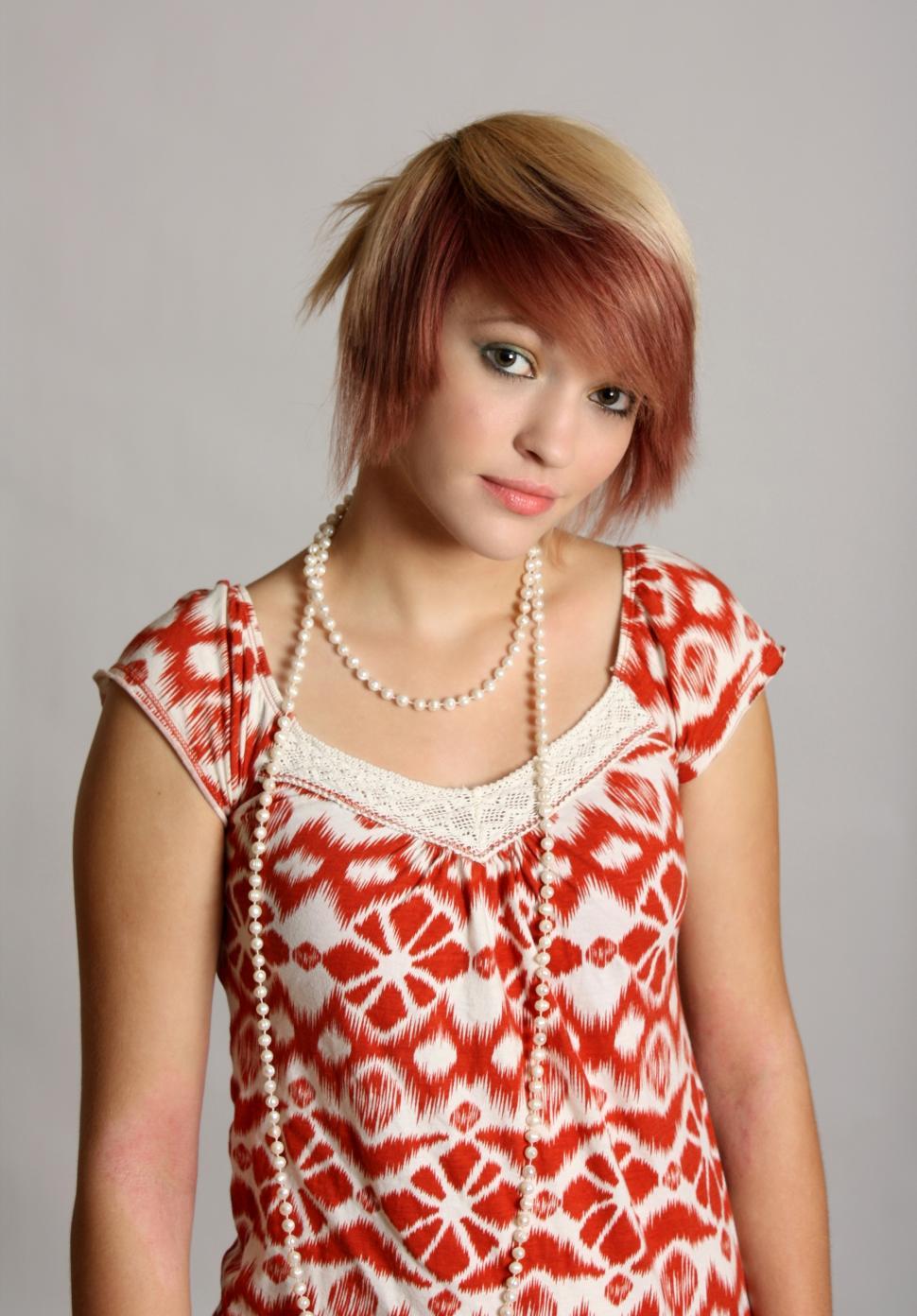 Free Image of A beautiful young woman wearing pearls posing on a gray background 
