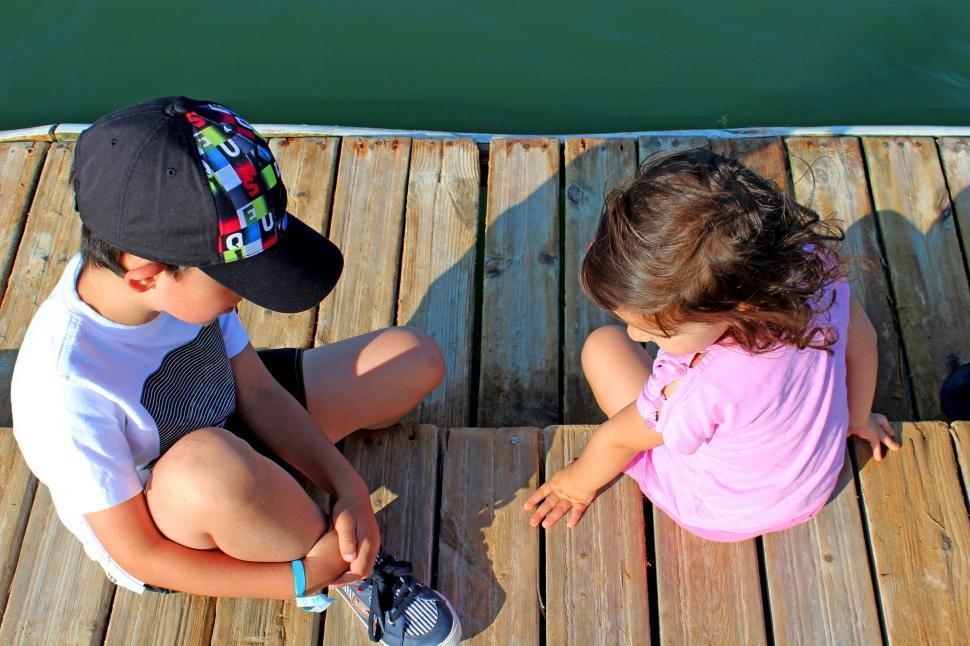 Free Image of A boy and a girl talking intimately on the pier 