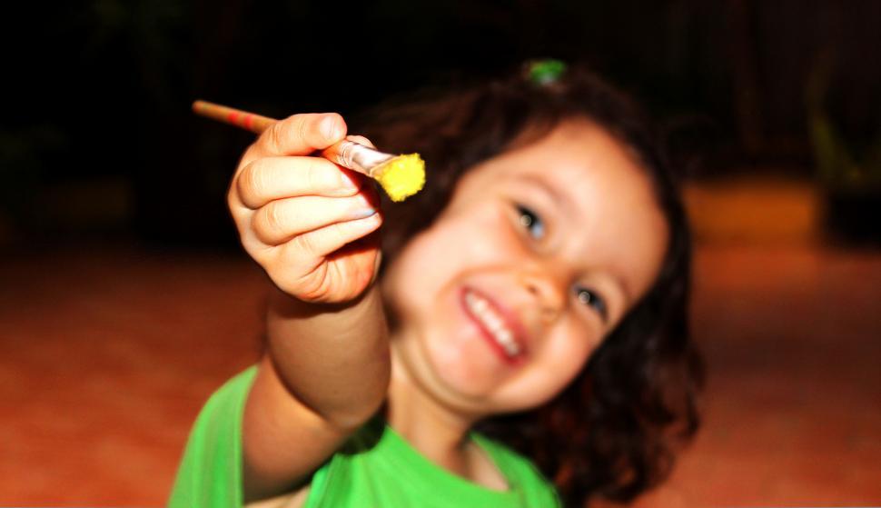 Free Image of Child holding and pointing forward a paintbrush 