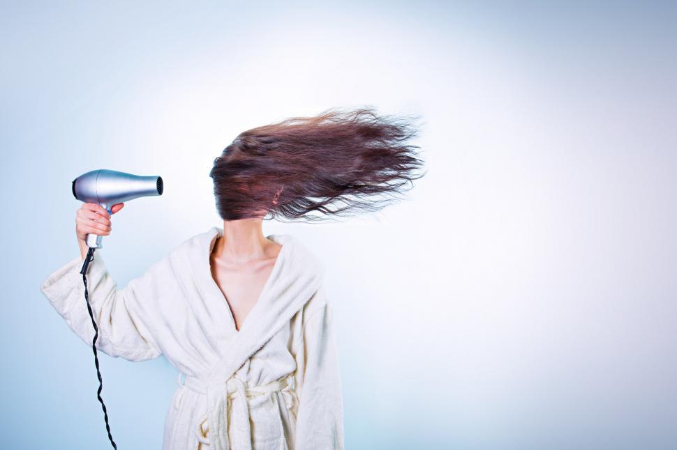 Free Image of Young woman blow drying hair 