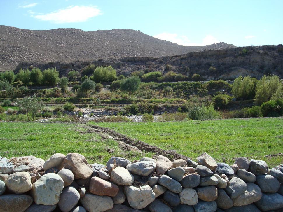 Free Image of Stone Wall in Field With Mountains Background 