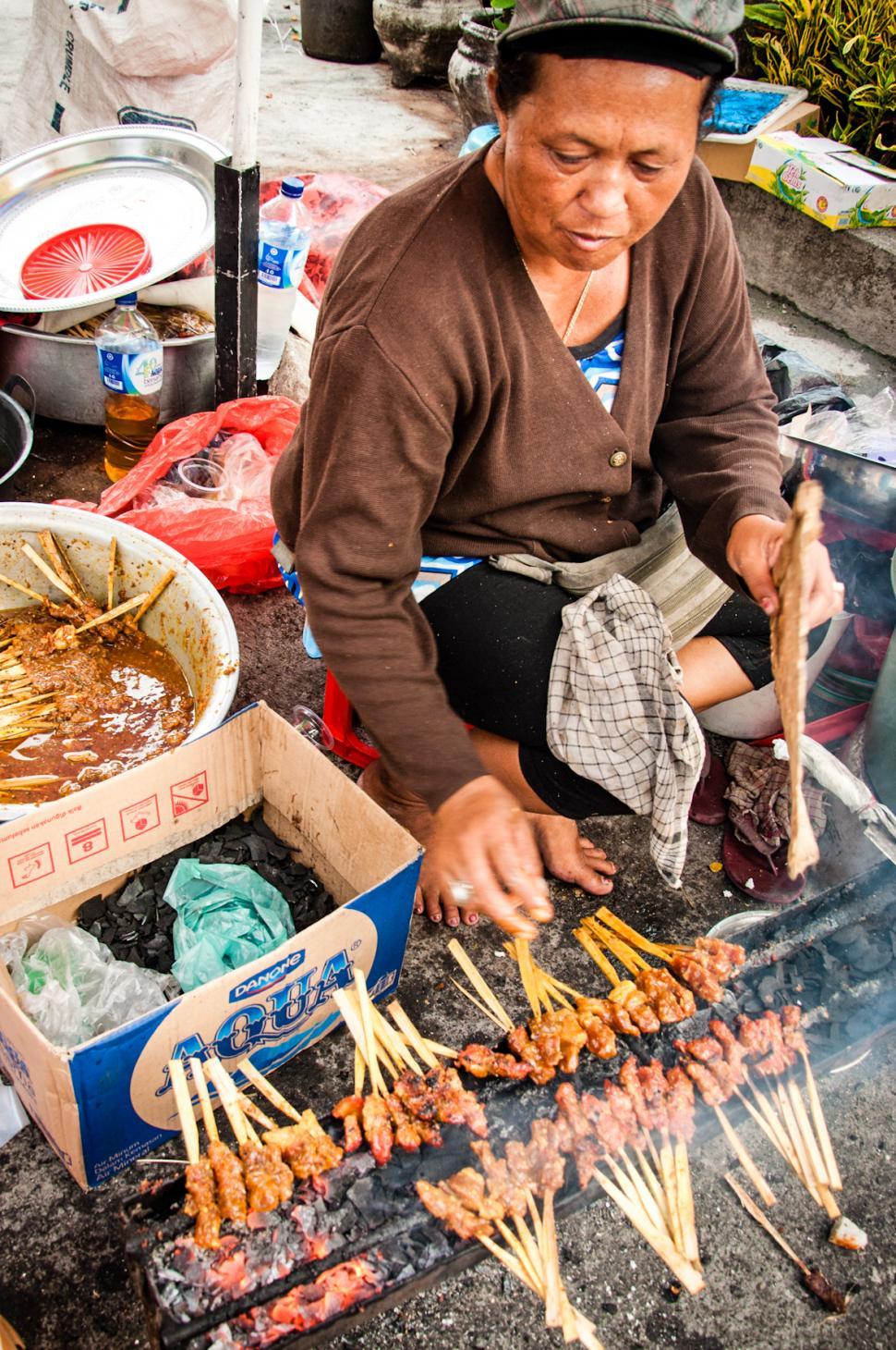Free Image of Asian woman selling sate on the street 