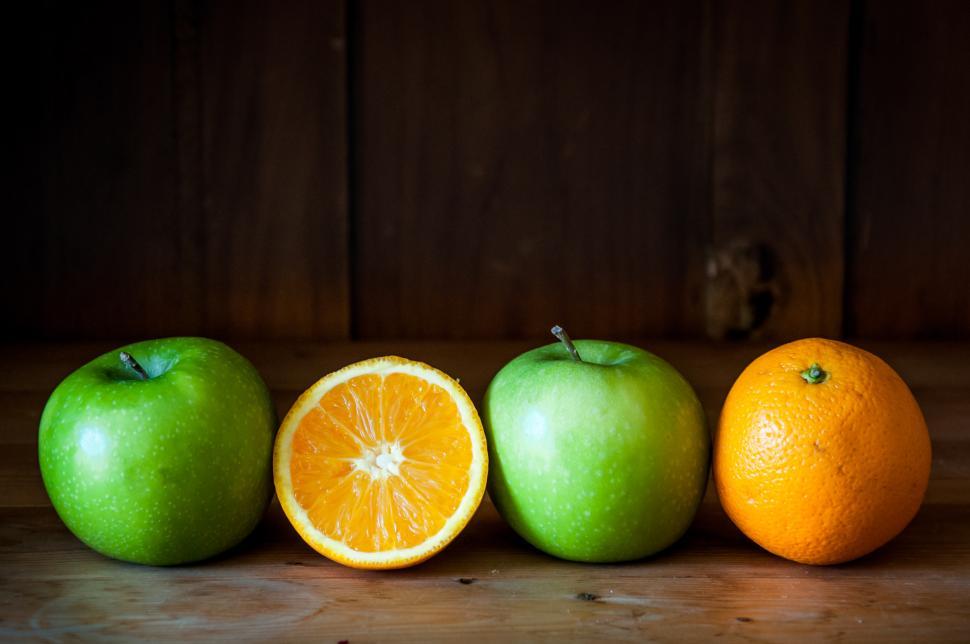 Free Image of Apple and orange fruit on brown wooden background 