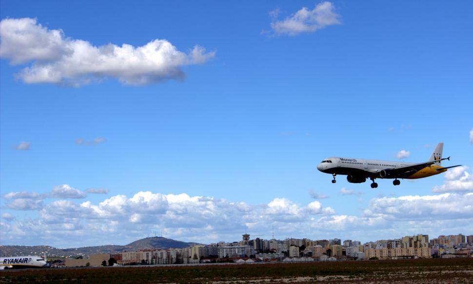 Free Image of Airplane Flying Over City Under Blue Sky 
