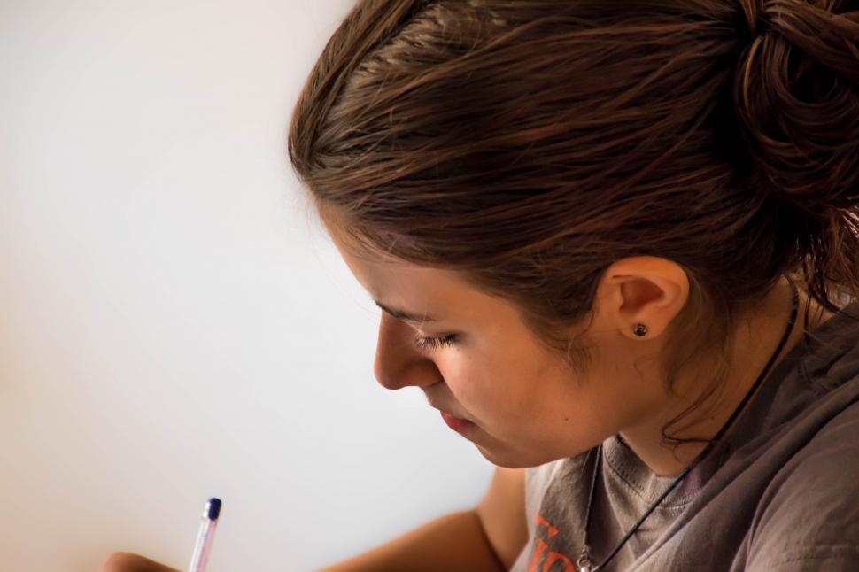 Free Image of Woman Writing on Piece of Paper 