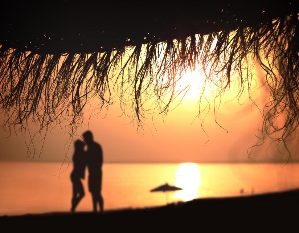 Free Image of Under the umbrella - A couple kisses at sunset 
