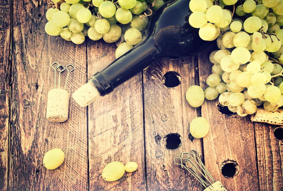 Free Image of Bottle of wine with grapes and corks on wooden table - Rustic loo 