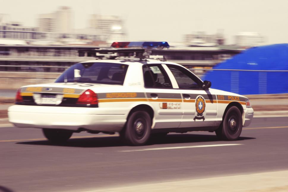 Free Image of Police Car Driving by Tall Building 