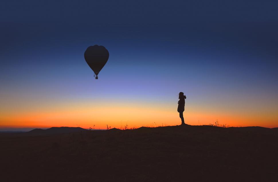 Free Image of A lone person observes an hot air balloon at sunrise 