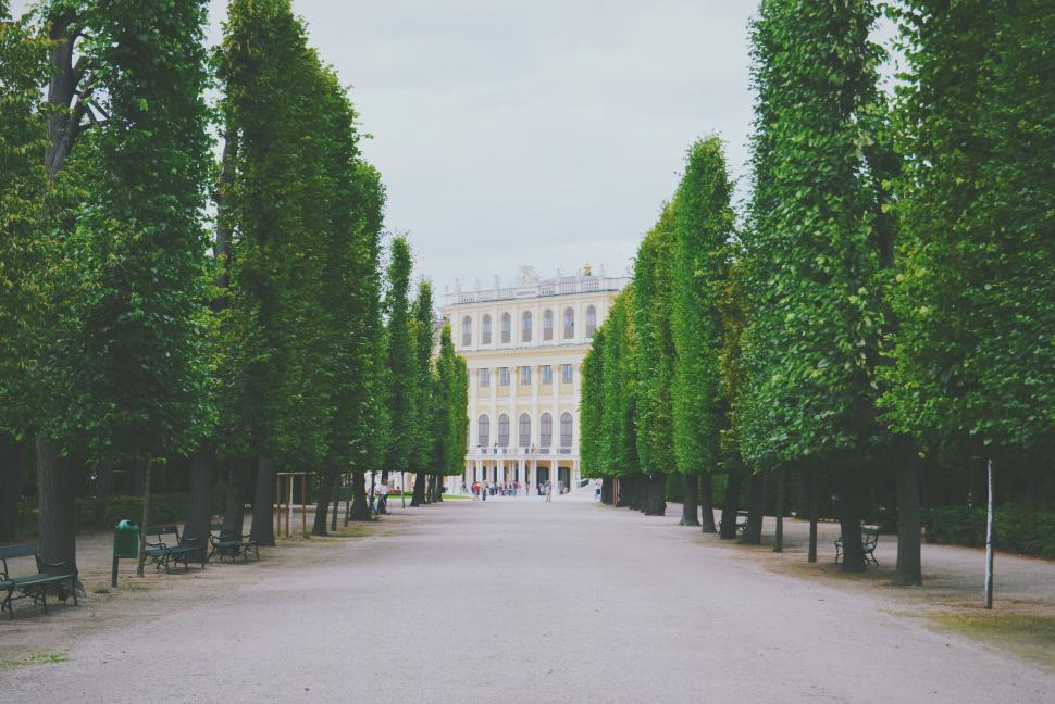 Free Image of Large White Building Surrounded by Trees and Benches 