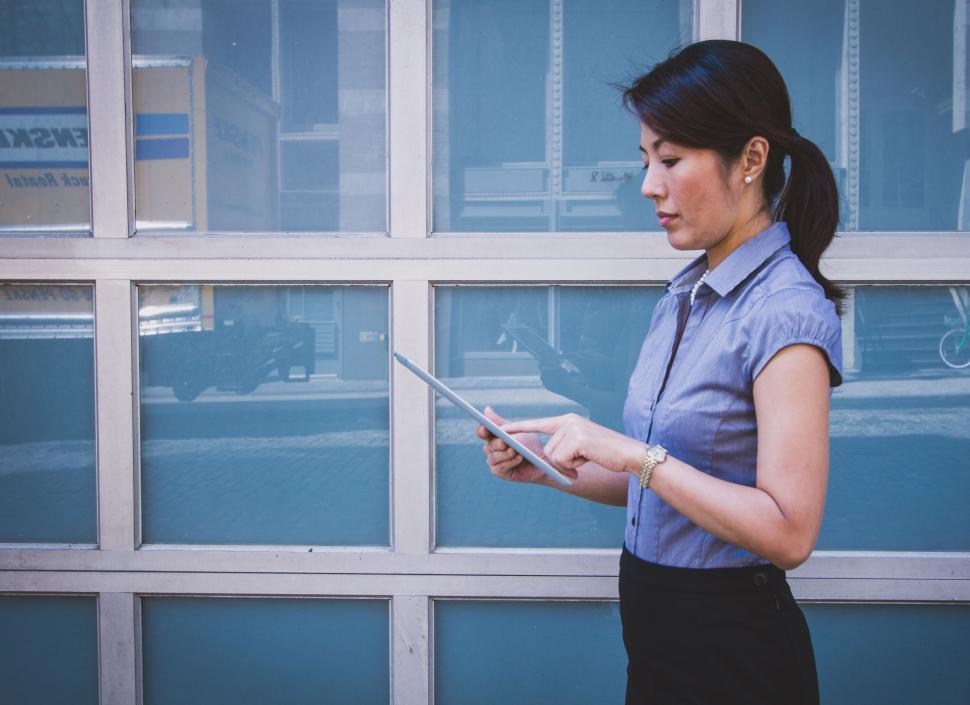 Free Image of Woman Standing in Front of Building Looking at Cell Phone 