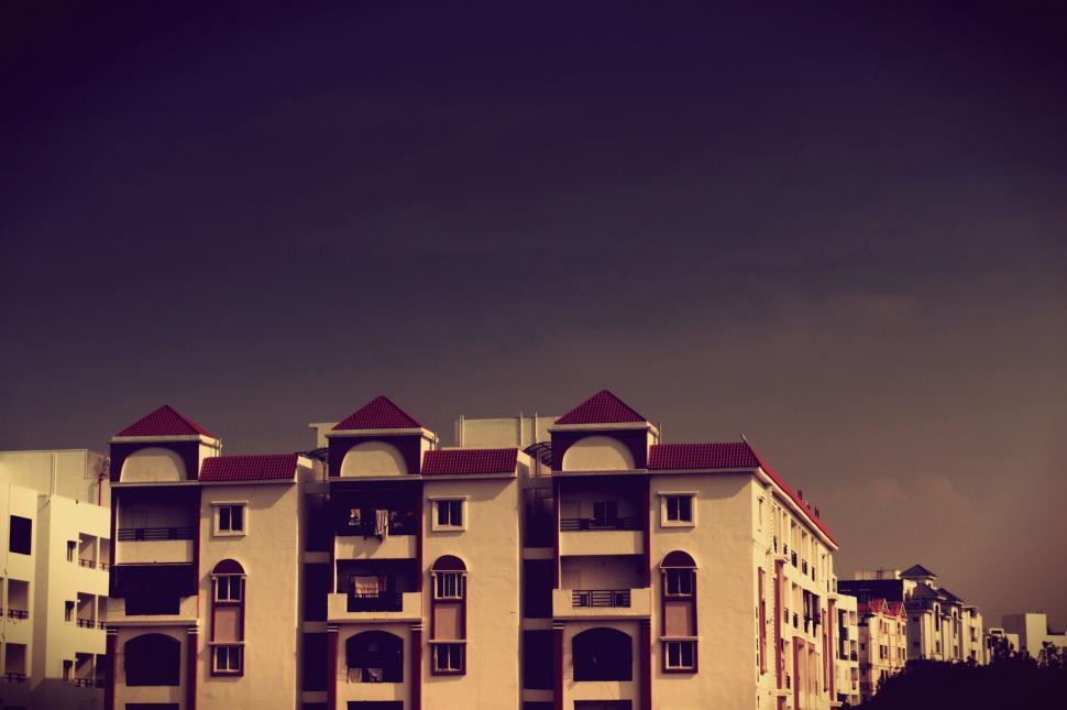 Free Image of Tall White Building Next to Lush Green Field 