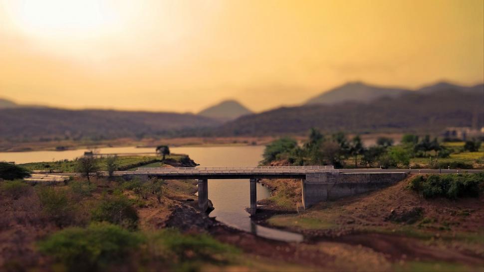 Free Image of Bridge Crossing River With Mountains in Background 