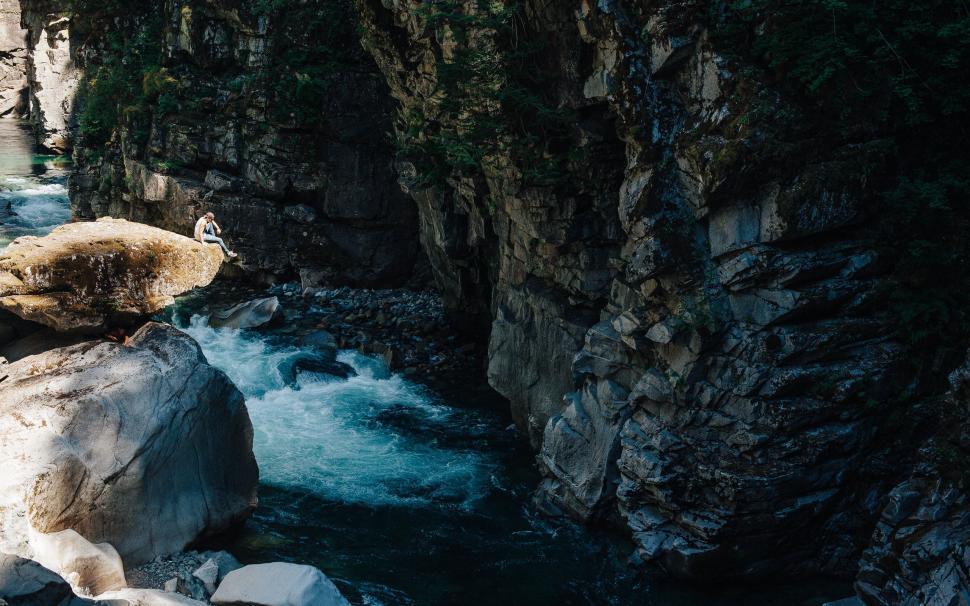 Free Image of Man Standing on Top of Rock by River 