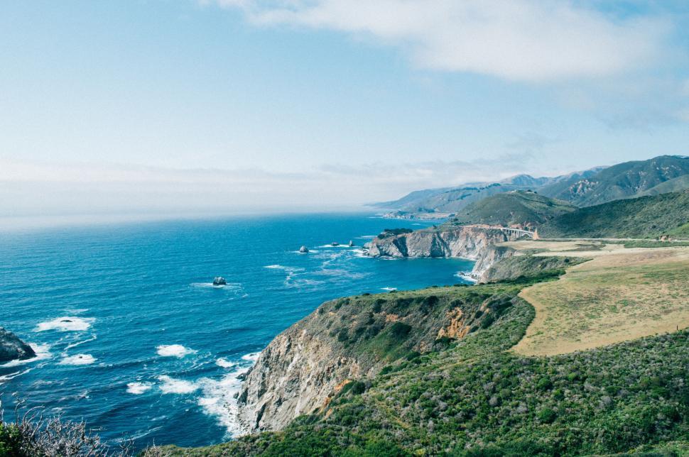 Free Image of Lush Green Hillside Overlooking Large Body of Water 