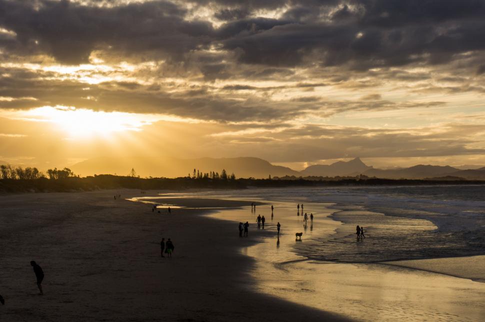 Free Image of Group of People Standing on Top of Beach Under Cloudy Sky 