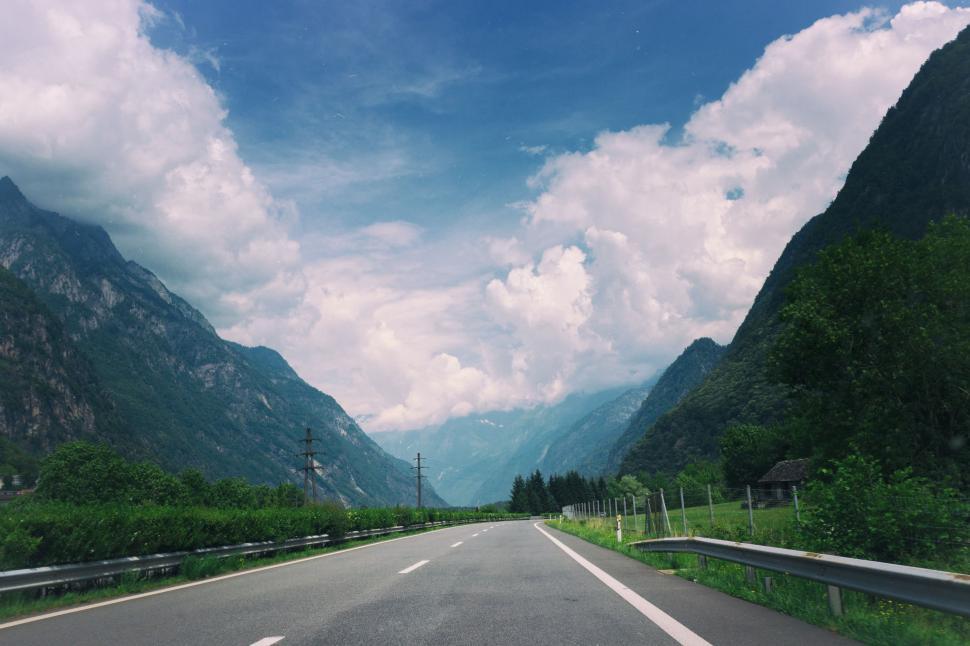 Free Image of Car Driving Down Road With Mountains in Background 