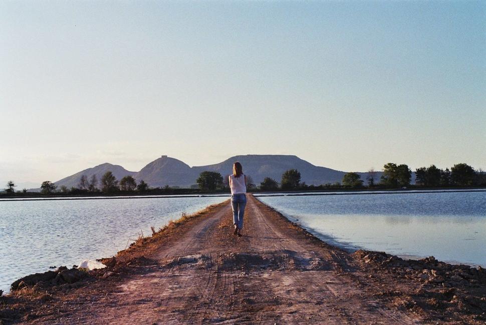 Free Image of Person Standing on Dirt Road Near Body of Water 