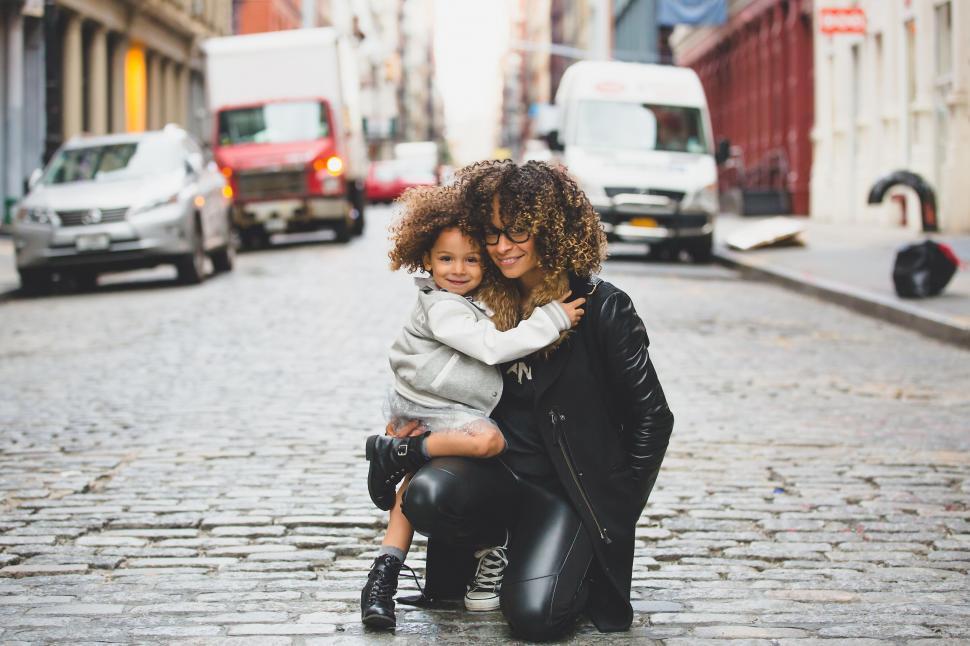Free Image of Woman Holding Child on Cobblestone Street 